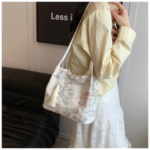 Dettaglio borsa tote in satin bianco con ricami cinesi e ciondolo con nappine di perle