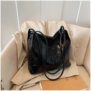 Gros plan sur la texture en cuir verni plissé d'un grand sac à main noir élégant et souple