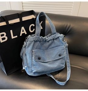 Detalle del bolso tote de mezclilla azul oscuro con cordón y bolsillos delanteros grandes