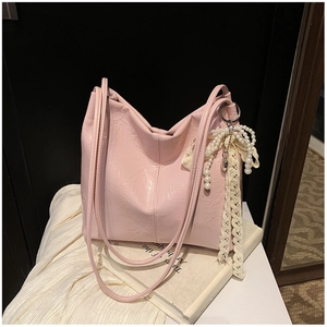 Gros plan du sac fourre-tout rose clair avec texture plissée et breloque perle