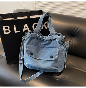 Detalle de bolso tote de mezclilla azul con asas dobles y bolsillo en sofá de cuero