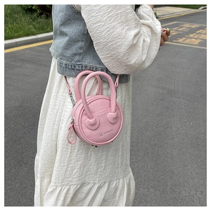 Detail of pink round handbag with heart decor and lychee texture in street style