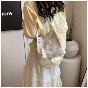 Dettaglio borsa a tracolla stile cinese con jacquard paesaggio e nappe bianche