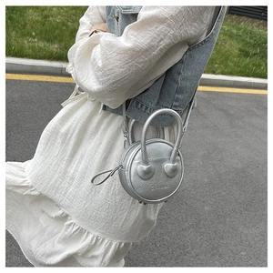 Detail of silver round mini crossbody bag with litchi texture and metallic finish