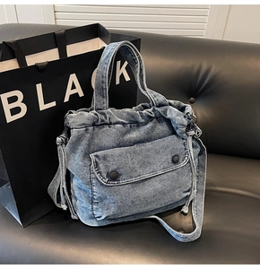 Detalle de bolso vaquero lavado azul claro con bolsillo de botón y cordones laterales