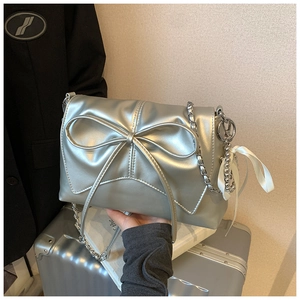 Detailed shot of silver bow handbag with chain strap and elegant side charm details
