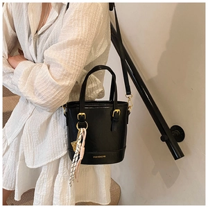 Close-up of black bucket bag featuring golden hardware and a colorful silk scarf accent