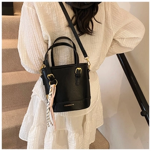 Detail view of black matte leather bucket bag with gold hardware and striped silk scarf