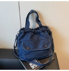 Detail der dunkelblauen Denim-Kordelzugtasche mit Vintage-Metallschnalle und Schultergurt