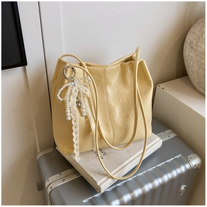 Gros plan du sac cabas jaune crème plissé avec nœud en dentelle et breloque perle