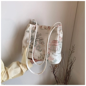 Dettaglio del ricamo di paesaggio cinese su borsa a secchiello beige con nappa