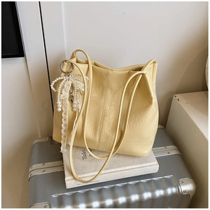 Détail du sac crème avec texture plissée et breloque noeud en dentelle et perles