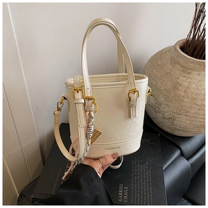 Detail of cream bucket bag with silk scarf, gold hardware and textured leather finish