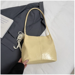 Détail d'un sac cabas plissé jaune crème avec breloque en perles et finition cuir lisse