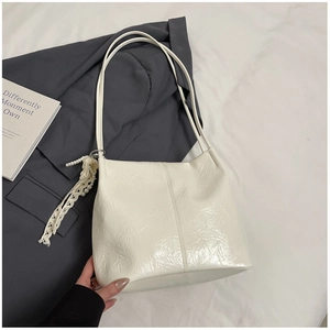 Détail du sac cabas blanc plissé avec breloque en dentelle et perles sur veste