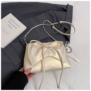 Close-up of elegant cream bow decoration and pearlescent texture on the shoulder bag