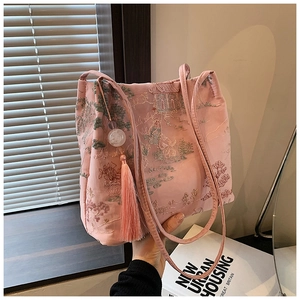 Dettaglio del ricamo jacquard in seta rosa con paesaggio verde e ciondolo con nappine