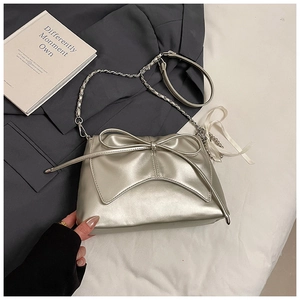 Detailed shot of metallic champagne gold handbag with bow decoration and chain strap