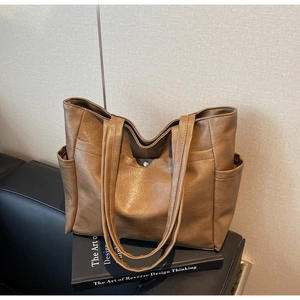 Close-up of brown PU leather tote bag featuring side pockets and a metal snap button detail