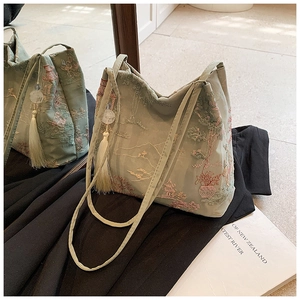 Dettaglio borsa tote verde fagiolo con ricamo tradizionale, nappina e riflesso nello specchio