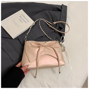 Detail of elegant satin crossbody bag with a large bow design and gold chain strap