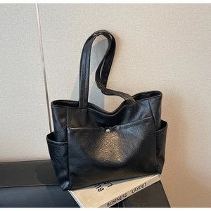 Detail of black faux leather tote bag showing vintage pleated texture and front pocket