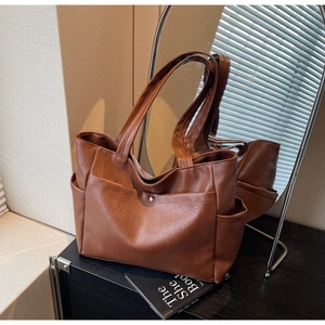 Macro shot of cognac tote bag detailing soft synthetic leather and silver magnetic closure