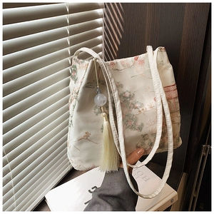 Dettaglio borsa a secchiello stile cinese bianco crema con ricamo floreale e nappa