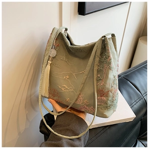 Dettaglio ravvicinato della borsa tote verde acqua con ricamo giardino cinese e nappa bianca