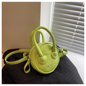 Macro detail of lime green mini round bag with lychee texture leather and heart design