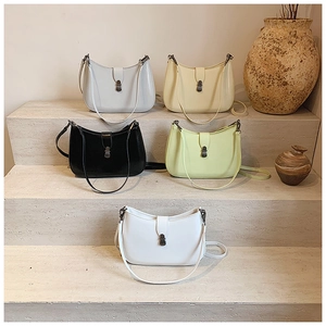Close-up of minimalist half-moon underarm bags in five colors on stone steps