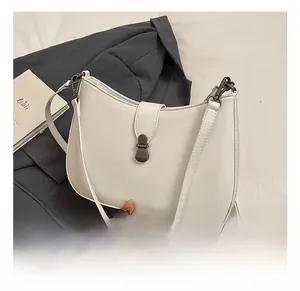 Detail of white semi-moon leather crossbody bag with a dark gray metal clasp