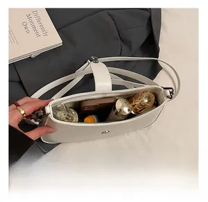Internal view of minimalist white leather underarm bag showing space for makeup and phone
