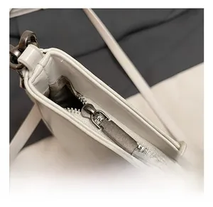 Macro detail of high-quality dark gold metal zipper and stitching on white leather bag