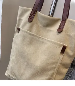 Detalle del bolso tote de lona beige con asas de cuero marrón y costuras reforzadas