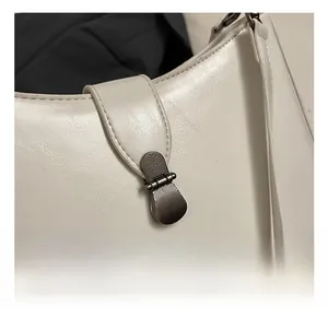 Detail of vintage gunmetal lock and fine texture on white minimalist shoulder bag