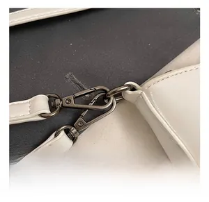 Detail showing high-quality metal swivel hook and precise stitching on white PU leather bag