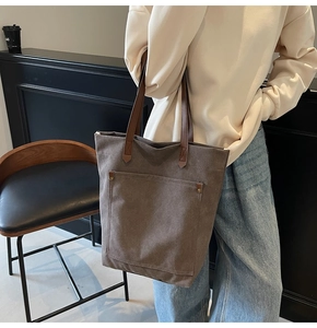 Detalle de un bolso tote grande de lona con remaches vintage y asas de cuero fino