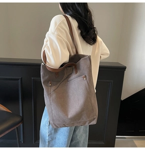Detalle del bolso tote de lona café con correas de cuero marrón y remaches metálicos