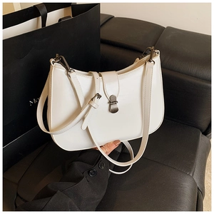 Detail of white leather crescent bag with vintage metal buckle on black leather background