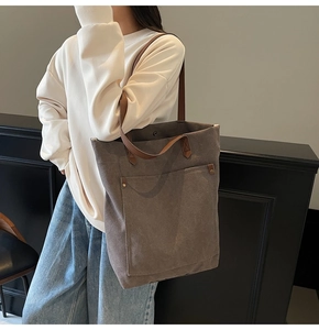 Detalle de bolso tote de lona con asas de cuero marrón y bolsillos con remaches de metal