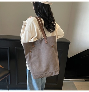 Detalle del bolso tote de lona grande con asas de cuero visto desde atrás en una modelo