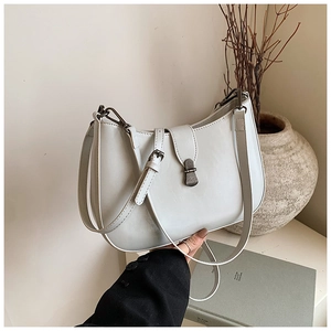 Detail of white minimalist half-moon shoulder bag with sleek metal buckle and matte leather