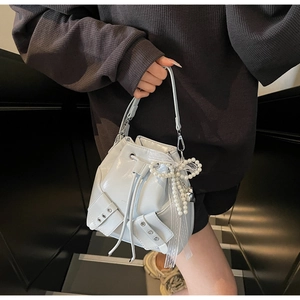 Gros plan du sac seau bleu clair avec pendentif nœud en perles et poche avant cloutée