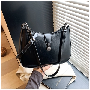 Close-up of black leather hobo bag with unique metal buckle and adjustable shoulder strap