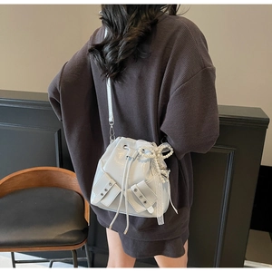 Détail du sac seau gris avec breloque en perles et dentelle et finition brillante