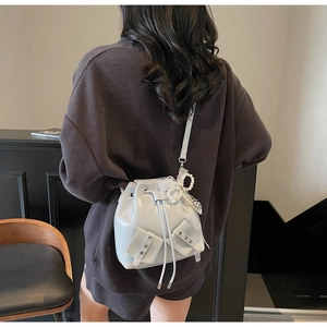 Vue de dos d'un sac seau plissé gris clair avec breloque perle et cordon de serrage