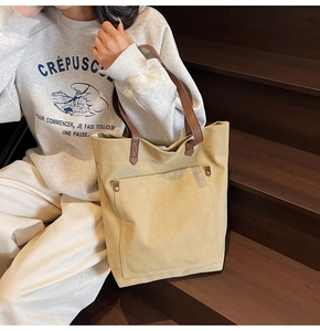Detalle de bolso tote de lona caqui con asas de cuero marrón y remaches de metal