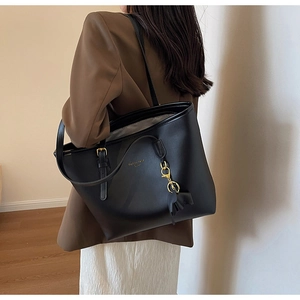 Black large capacity tote bag with gold lettering shown on shoulder for daily commute