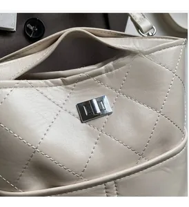 Dettaglio della borsa a secchiello trapuntata beige con chiusura a scatto quadrata argento